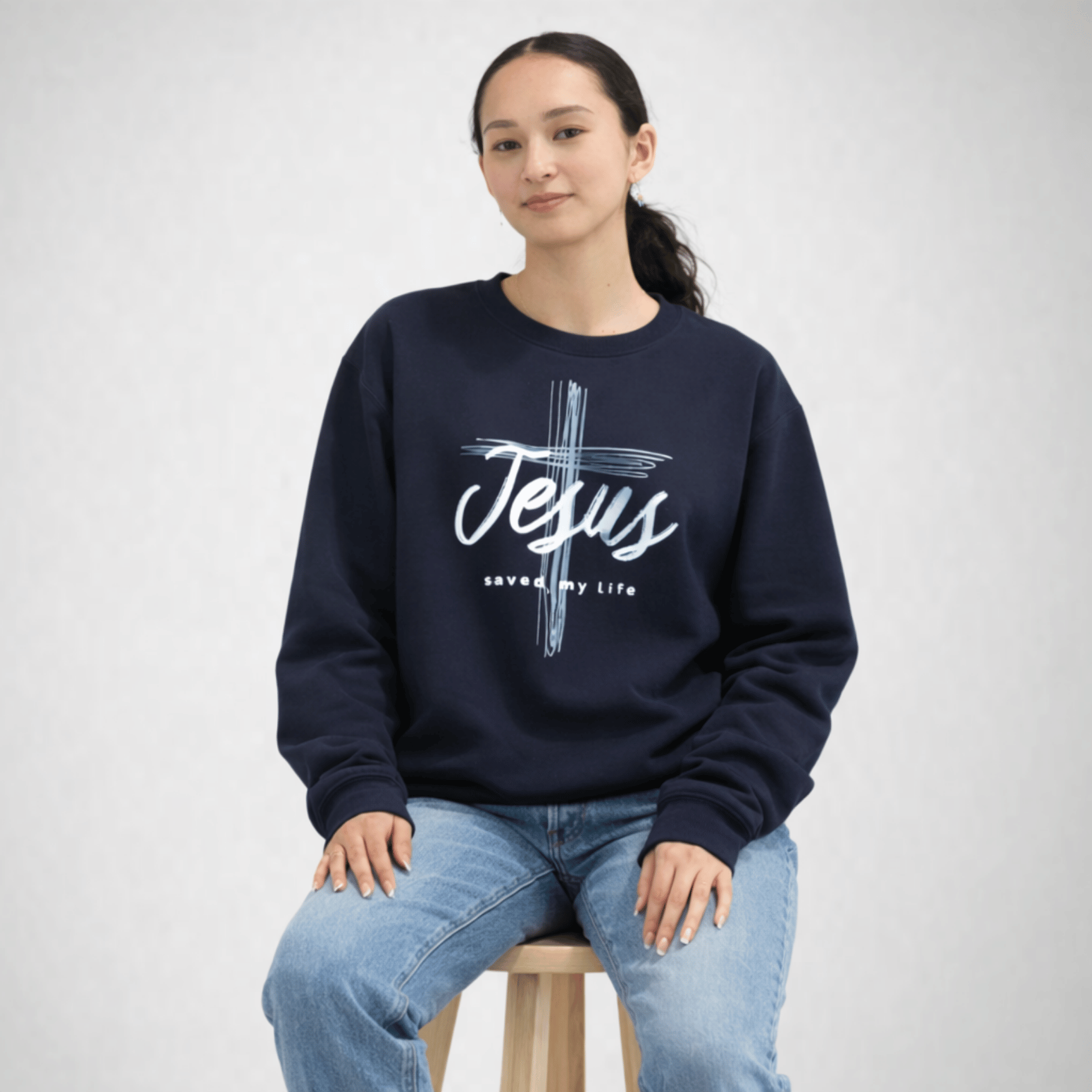 Person wearing a navy sweatshirt with 'Jesus saved my life' text on a white background