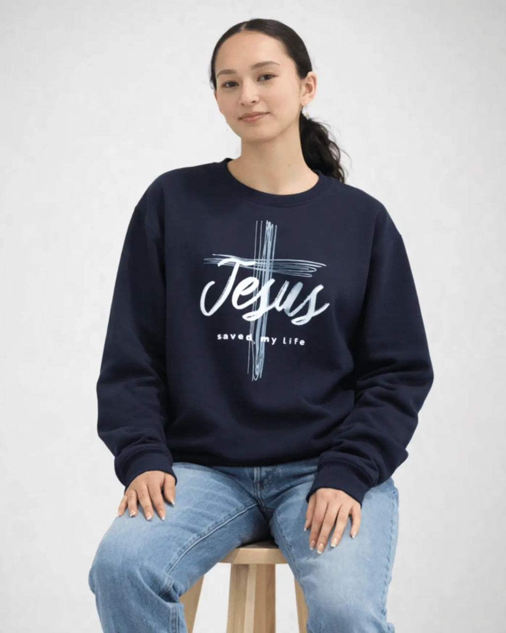 Person wearing a navy sweatshirt with 'Jesus saved my life' text on a white background
