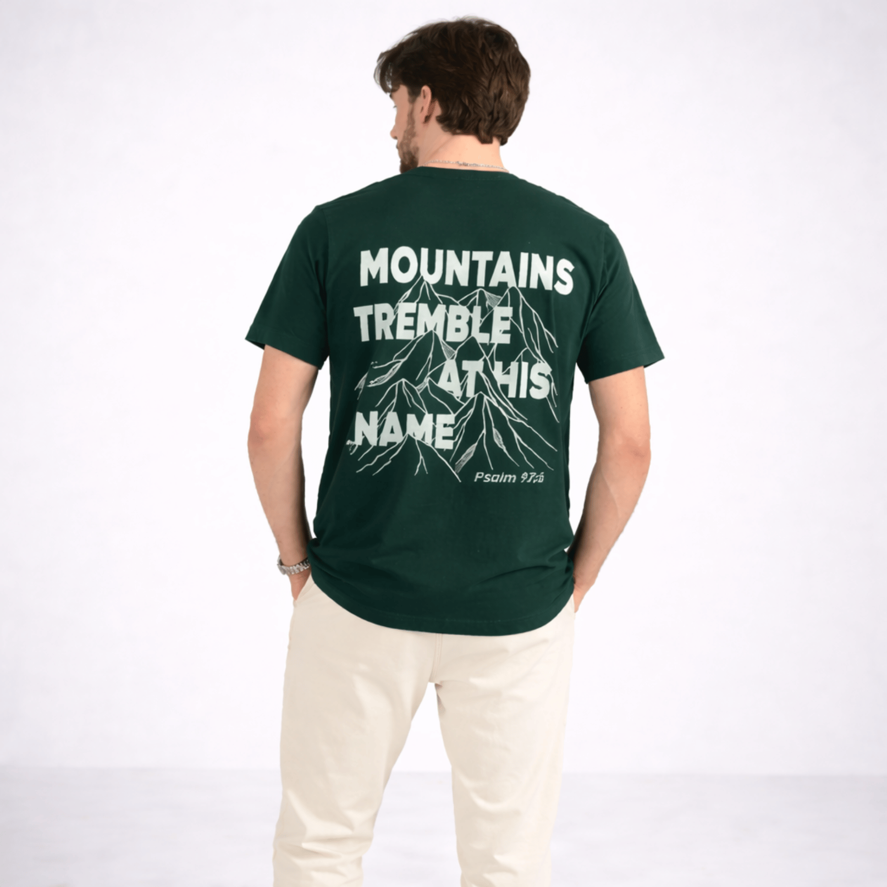 Person wearing a green t-shirt with text and mountain graphic on the back, on a white background