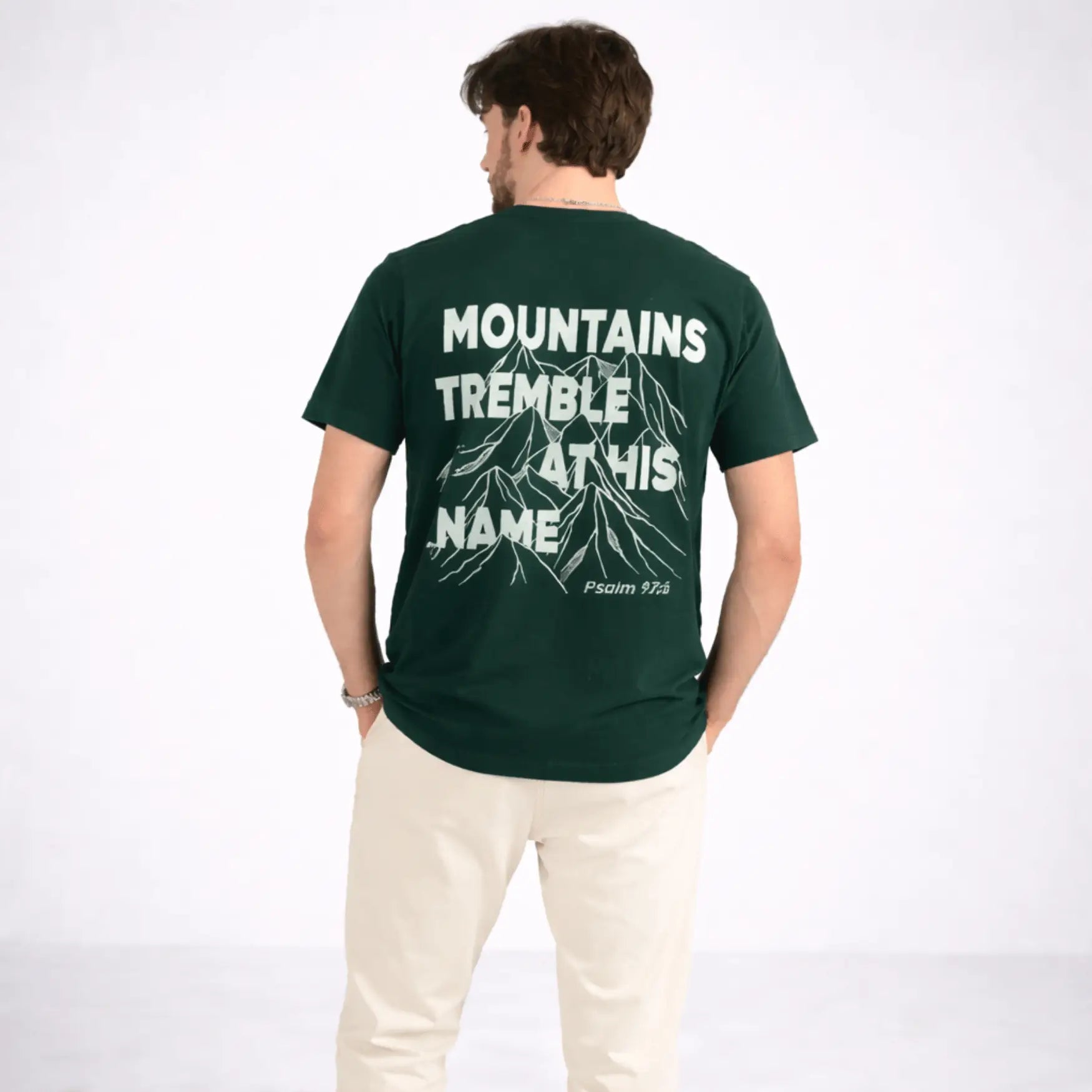 Person wearing a green t-shirt with text and mountain graphic on the back, on a white background