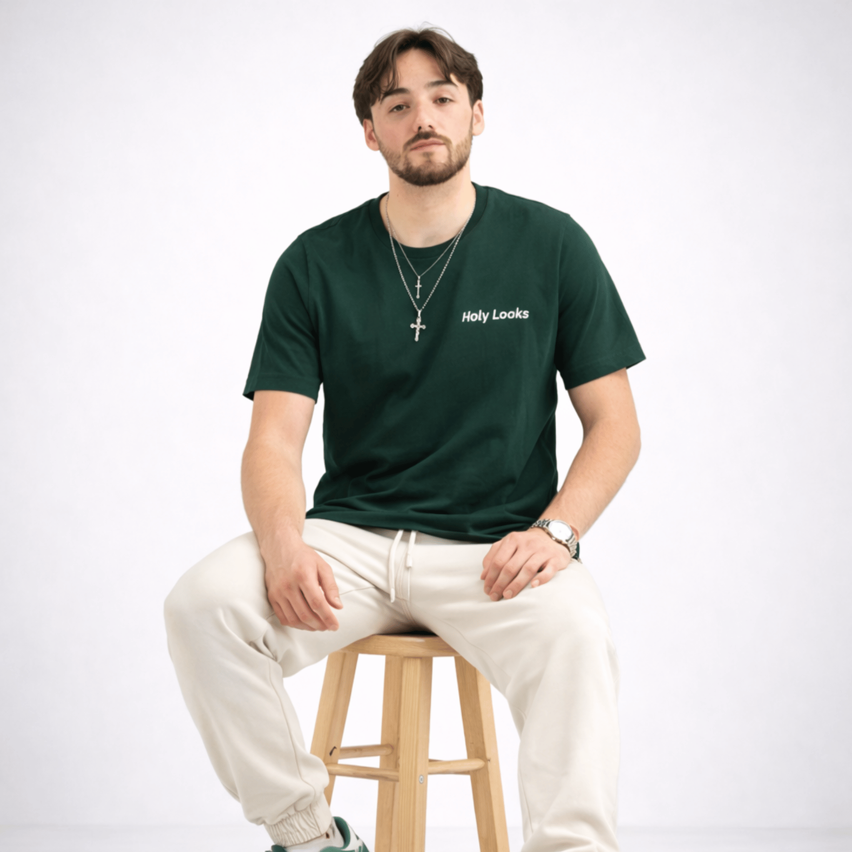 Man sitting on a stool wearing a green t-shirt with 'Holy Looks' text.