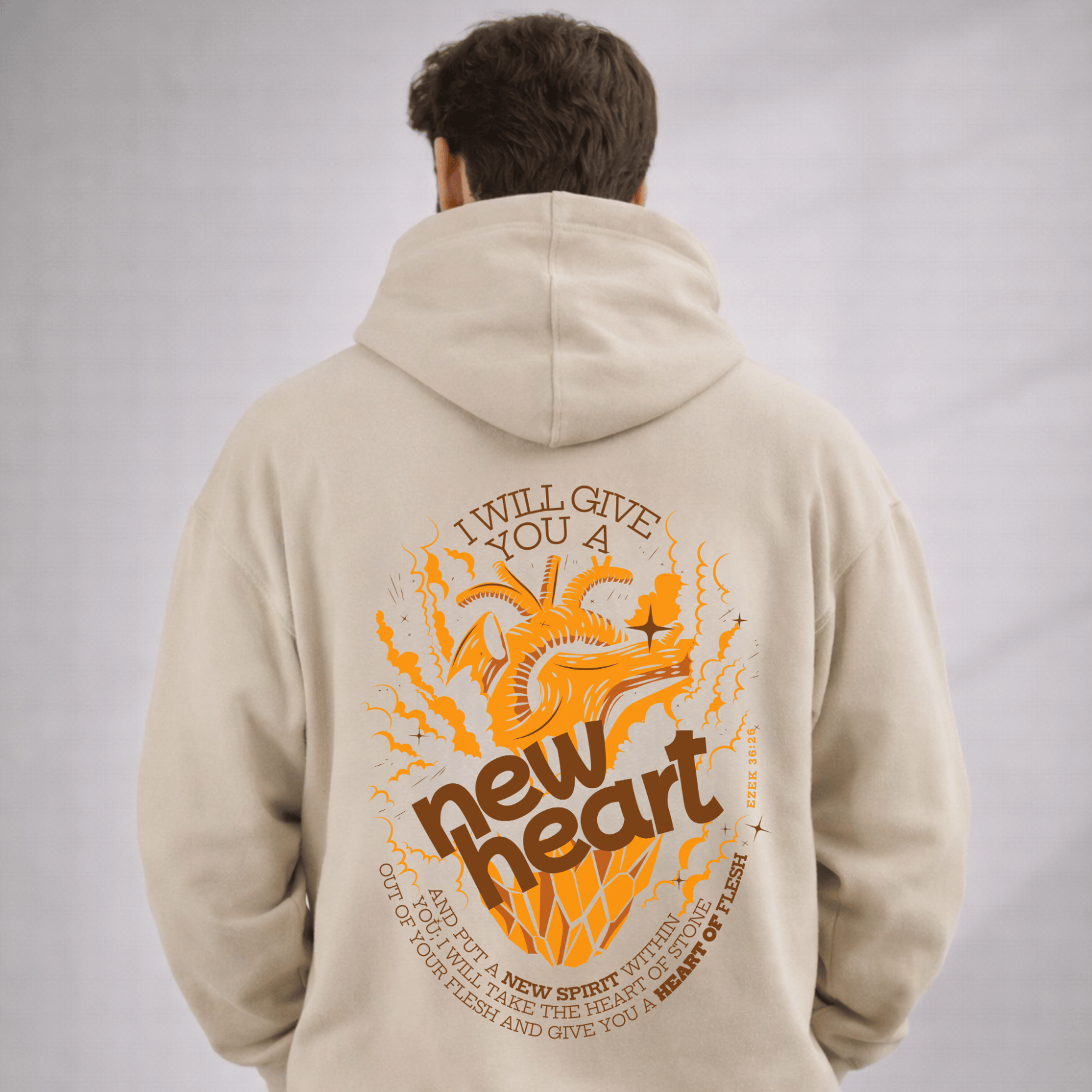 Person wearing a beige hoodie with an orange and brown graphic and text on the back against a gray background