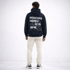 Person wearing a navy hoodie with text on the back, standing against a white background