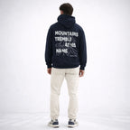Person wearing a navy hoodie with text on the back, standing against a white background