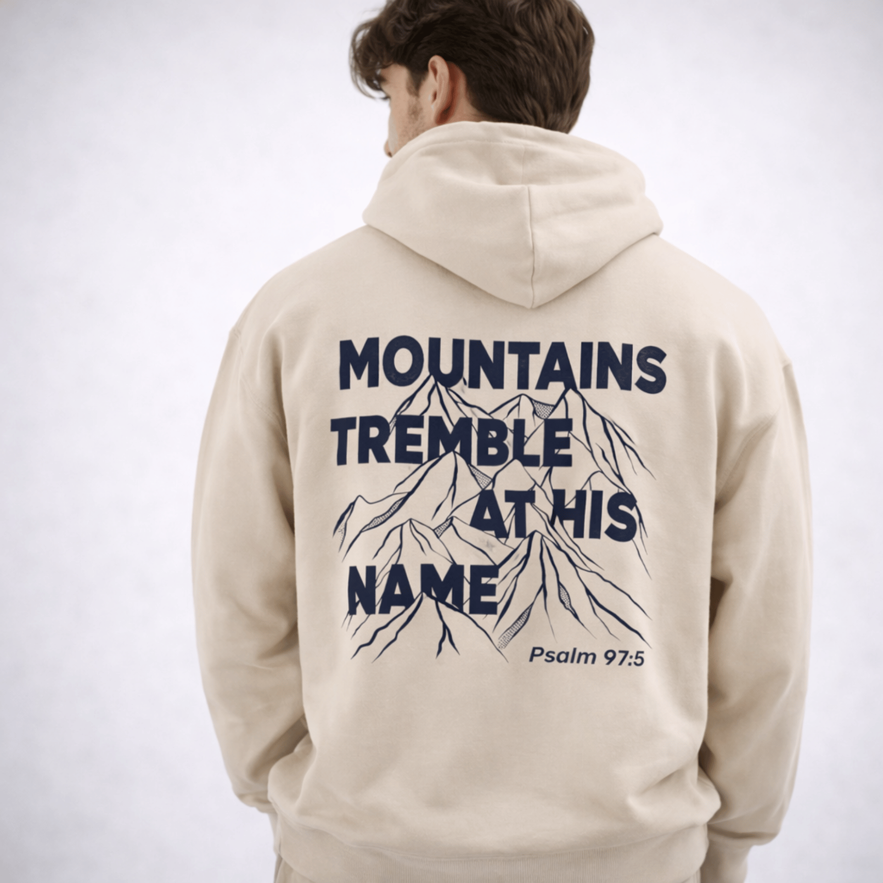 Beige hoodie with mountain graphic and text on the back, worn by a person.