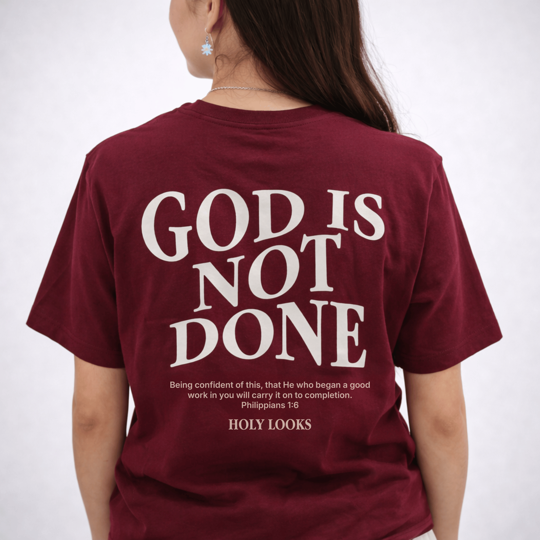 Maroon t-shirt with 'God is Not Done' text on the back, worn by a person.