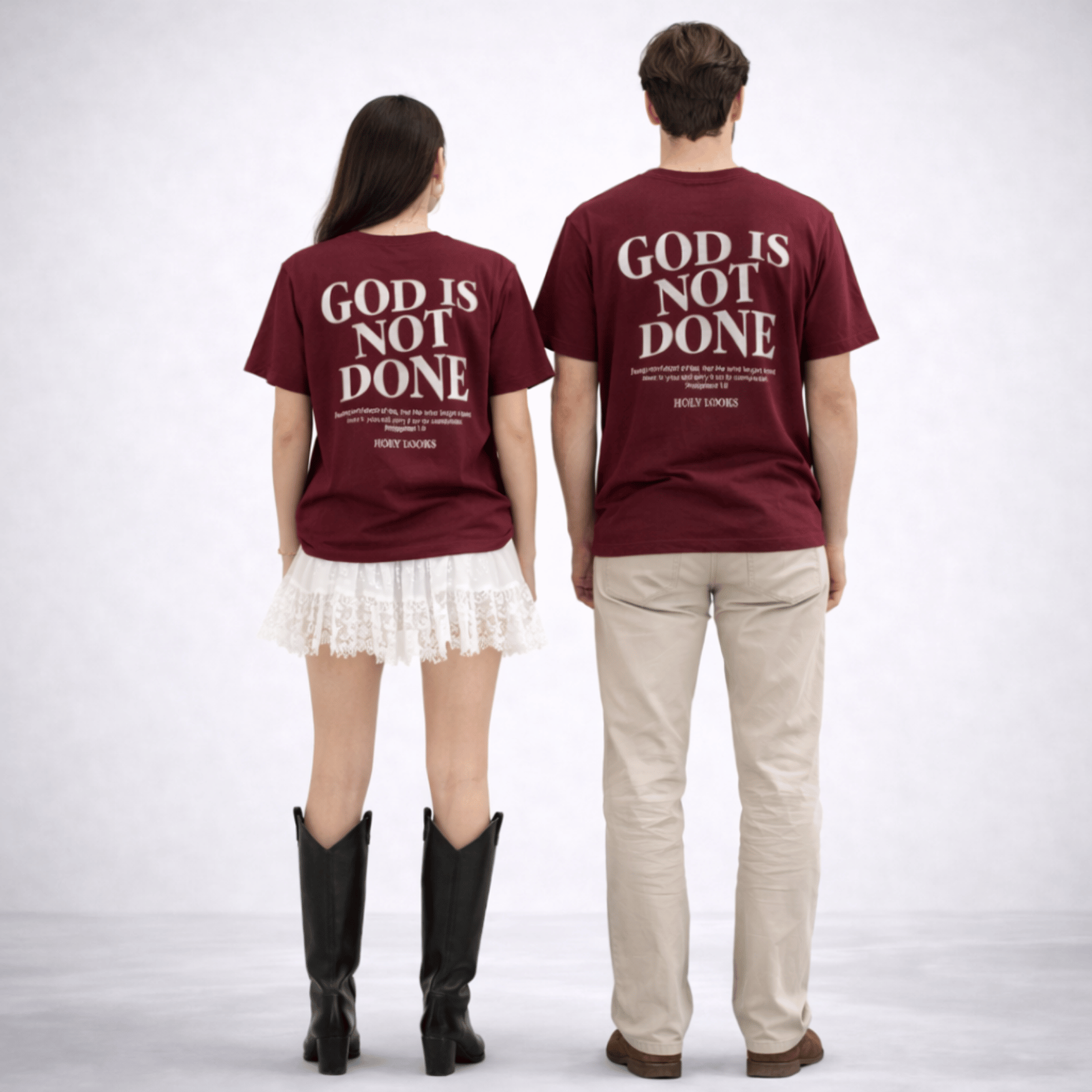 Two people wearing maroon t-shirts with 'GOD IS NOT DONE' text on a white background