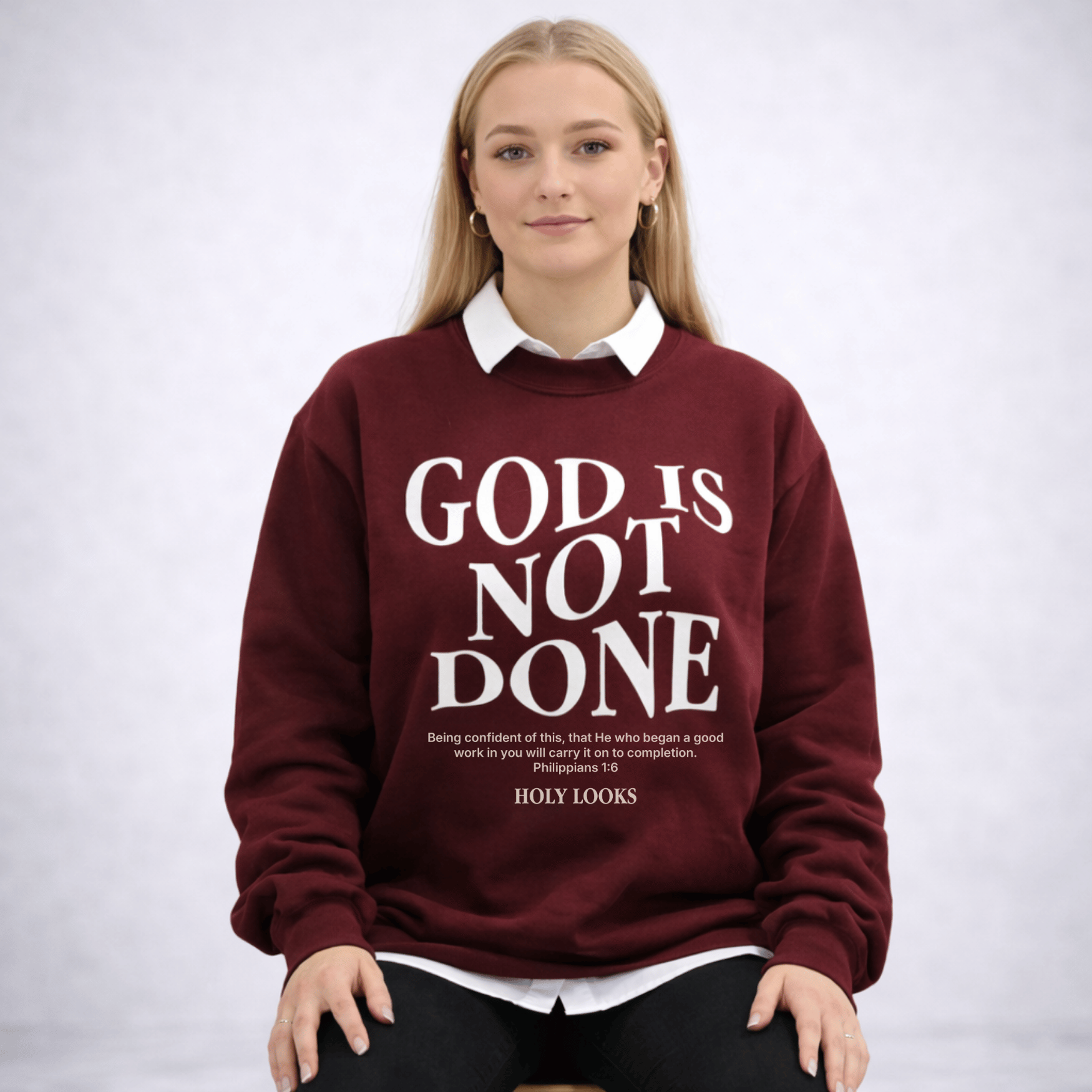 Person wearing a maroon sweatshirt with 'GOD IS NOT DONE' text on a white background