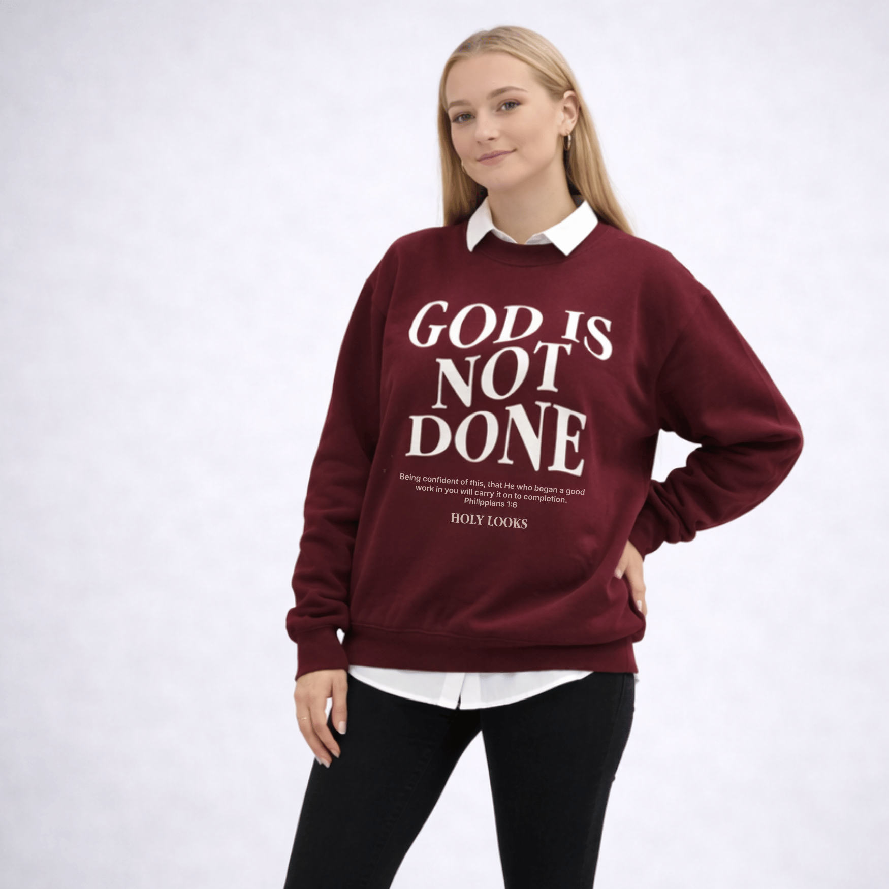 Person wearing a maroon sweatshirt with 'GOD IS NOT DONE' text on a light gray background