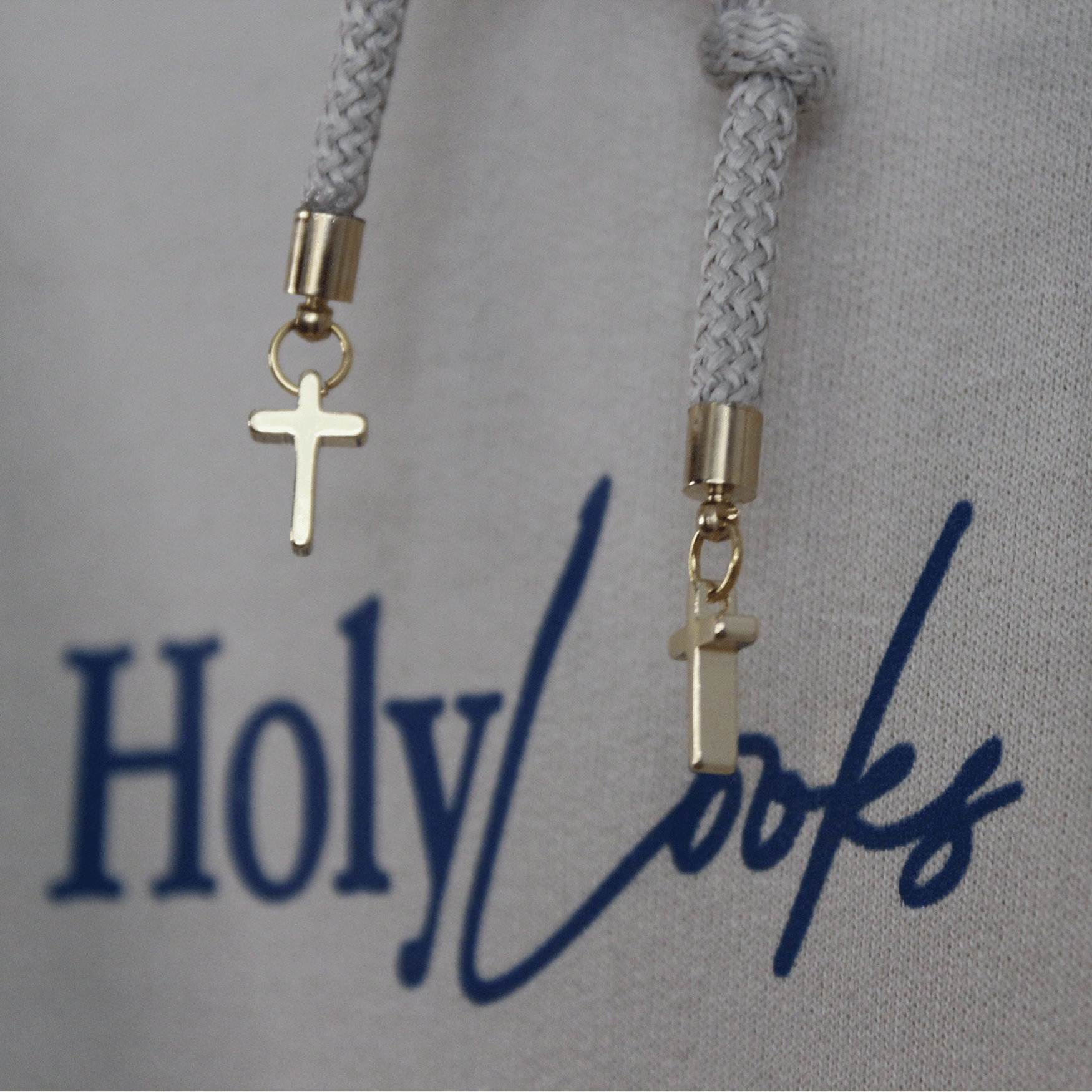 Gray hoodie with 'Holy Looks' text and cross charm on a gray background