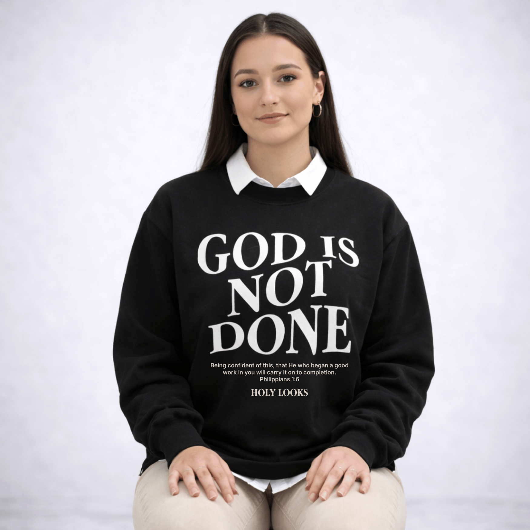Person wearing a black sweatshirt with 'God is not done' text on a white background