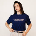 A woman wearing a navy blue t-shirt with white printed text that reads 'THE LORD RENEWING THE STRENGTH OF THOSE WHO TRUST IN HIM.' She is also wearing beige pants and a black belt, standing against a plain off-white background.