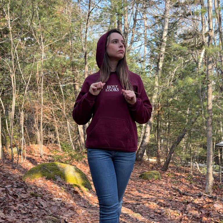Person wearing a maroon hoodie with text in a forest setting