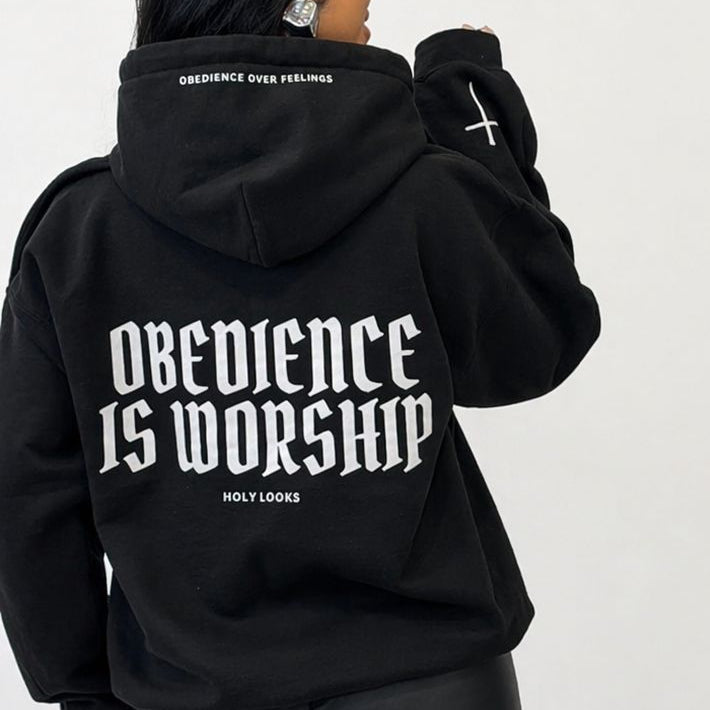 Person wearing a black hoodie with 'Obedience is Worship' text on the back, standing against a white background.